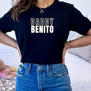 May include: A black t-shirt with white text that reads "DADDY BENITO".