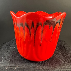 May include: A vibrant red glass bowl featuring a scalloped, wavy rim and a distinctive black drip pattern cascading from the top edge down the sides. The bowl has a smooth, glossy finish and a rounded base, showcasing a bold contrast of colors.