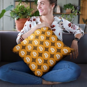 May include: A brown and yellow throw pillow with a repeating pattern of white Bitcoin symbols.