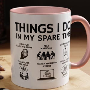 White ceramic mug with pink handle featuring funny mahjong lover design “Things I Do In My Spare Time,” perfect for players and mahjong fans.