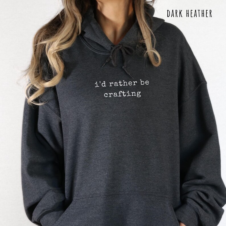 Pu&ograve; includere: Felpa con cappuccio grigio scuro con la scritta bianca "i'd rather be crafting". La felpa ha un cappuccio con coulisse e una tasca frontale. Le parole "Dark Heather" sono stampate nella parte superiore dell'immagine. Una felpa casual e confortevole.