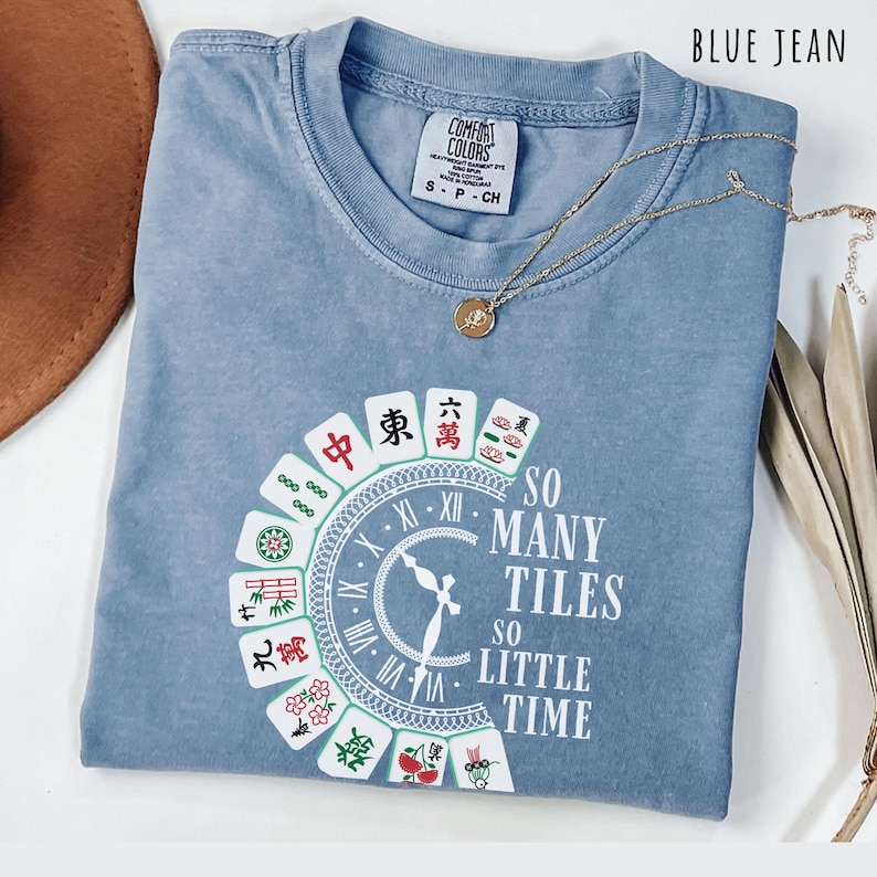 Blue jean comfort colors shirt with the phrase “So Many Tiles So Little Time” and colorful mahjong tiles surrounding a clock design, perfect for mahjong lovers and game night fans.