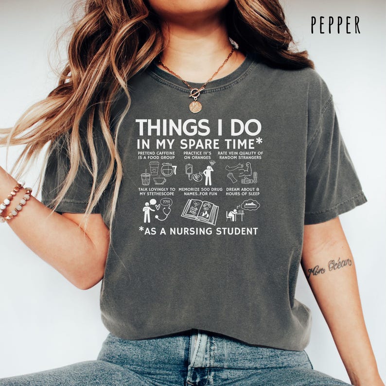 Peut inclure: T-shirt gris fonc&eacute; avec l'inscription blanche : "THINGS I DO IN MY SPARE TIME* AS A NURSING STUDENT", accompagn&eacute;e d'illustrations. Le t-shirt est de style d&eacute;contract&eacute;, id&eacute;al pour un usage quotidien.