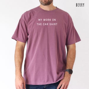 May include: Berry-colored t-shirt with the text "MY WORK ON THE CAR SHIRT" in white. The short-sleeved shirt is a solid color and has a relaxed fit. The word "BERRY" is printed in the upper right corner.