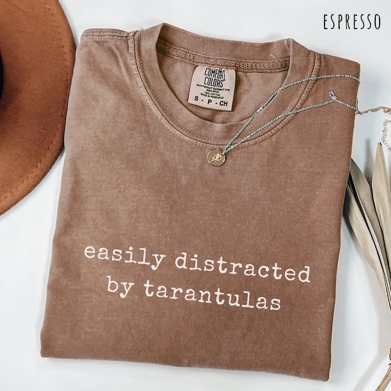 Brown tarantula themed shirt with minimalist white text design for spider lovers and arachnid fans. Funny tarantula t shirt perfect for exotic pet keepers spider enthusiasts insect collectors terrarium hobbyists arachnology fans creepy critter lovers and anyone obsessed with tarantulas. A unique casual gift for spider and bug lovers.