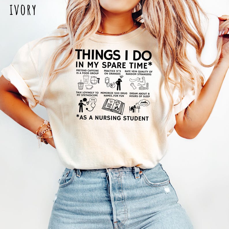 Peut inclure: T-shirt ivoire avec l'inscription "THINGS I DO IN MY SPARE TIME* AS A NURSING STUDENT" et diverses petites illustrations noires. Le t-shirt a un col rond et des manches courtes.