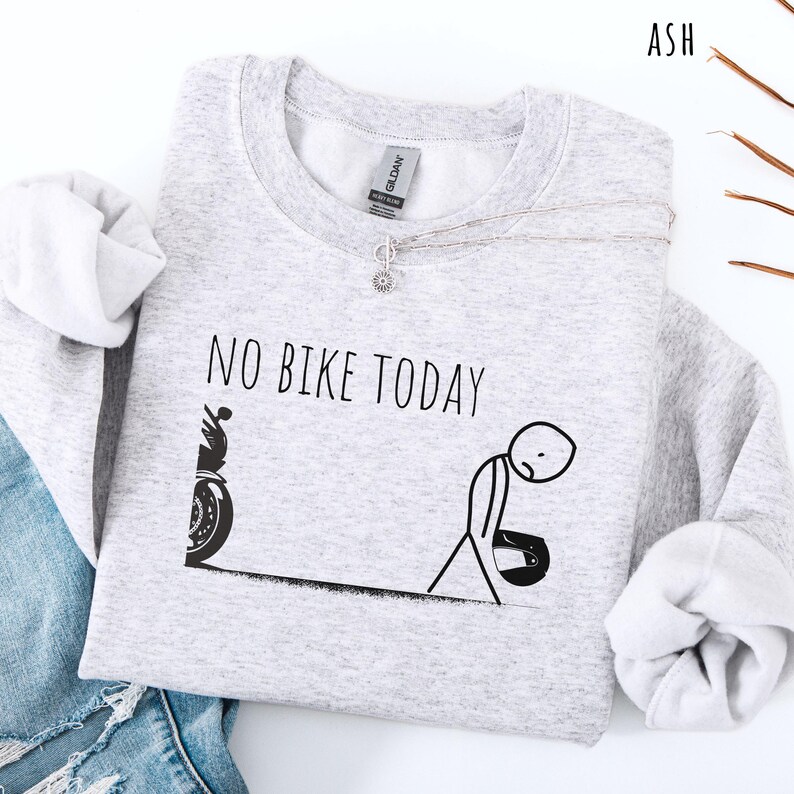 May include: Light gray sweatshirt with the text "NO BIKE TODAY" and a stick figure design. The design includes a motorcycle and a dejected person holding a helmet. The sweatshirt has long sleeves and a crew neck.