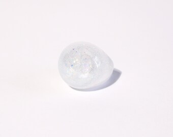 May include: A clear, white, egg-shaped ornament filled with iridescent glitter.