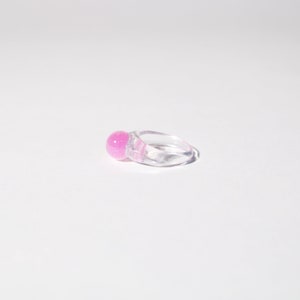 Peut inclure: Une bague en plastique transparente avec une sphère rose scintillante à l'avant.