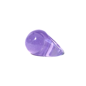 Peut inclure: Une bague violette avec une finition scintillante. La bague est en résine et a une forme asymétrique unique.