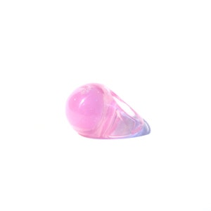 May include: A pink ring with a large, round, translucent stone. The ring is made of clear plastic and has a shiny finish.