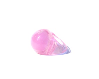 May include: A pink ring with a large, round, translucent stone. The ring is made of clear plastic and has a shiny finish.