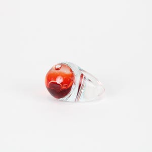 以下が含まれることがあります： 涙の形をした透明なガラスのアートオブジェクト。オブジェクトは、バブルのようなデザインの赤い球状の内部を持っています。透明なガラスの外側には、上部に小さな泡があります。オブジェクトは白い背景にあります。