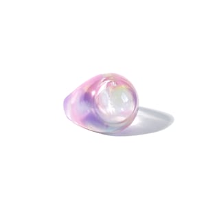 May include: A ring featuring a large, iridescent, oval-shaped stone. The stone is a light pink and purple colour with a white centre.