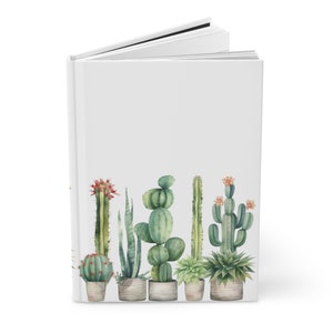 Puede incluir: Un diario blanco con una ilustración de acuarela de una fila de cactus y suculentas en macetas. Los cactus son verdes y tienen flores rosas. Las suculentas son verdes y tienen flores blancas.