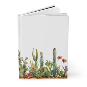 May include: A white hardcover journal with a watercolor illustration of a row of cacti and succulents on the bottom edge. The cacti are green and have pink, orange, and yellow flowers.