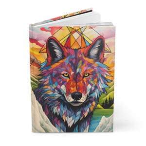 May include: A colorful geometric wolf illustration on a journal cover. The wolf's fur is made up of many different colored triangles and squares. The background is a sunset scene with mountains and a lake.