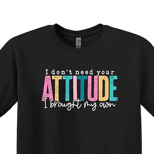 K&ouml;nnte beinhalten: Schwarzes T-Shirt mit dem Text "I don't need your ATTITUDE I brought my own" in bunten Buchstaben.