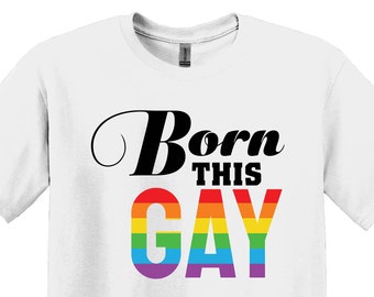 May include: White t-shirt with the text "Born This Gay" in black lettering with a rainbow stripe design behind the word "Gay".