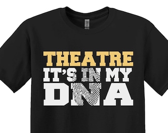 Puede incluir: Camiseta negra con el texto "THEATRE IT'S IN MY DNA" en dorado y blanco. El diseño incluye un gráfico de huella dactilar dentro de la palabra "DNA". La camiseta es de cuello redondo.