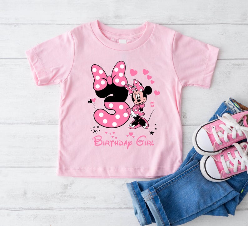 May include: Pink t-shirt with a Minnie Mouse design and the number 3. The shirt says "Birthday Girl".