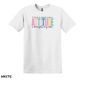 K&ouml;nnte beinhalten: Wei&szlig;es T-Shirt mit dem Text "I don't need your ATTITUDE I brought my own" in bunten Buchstaben.