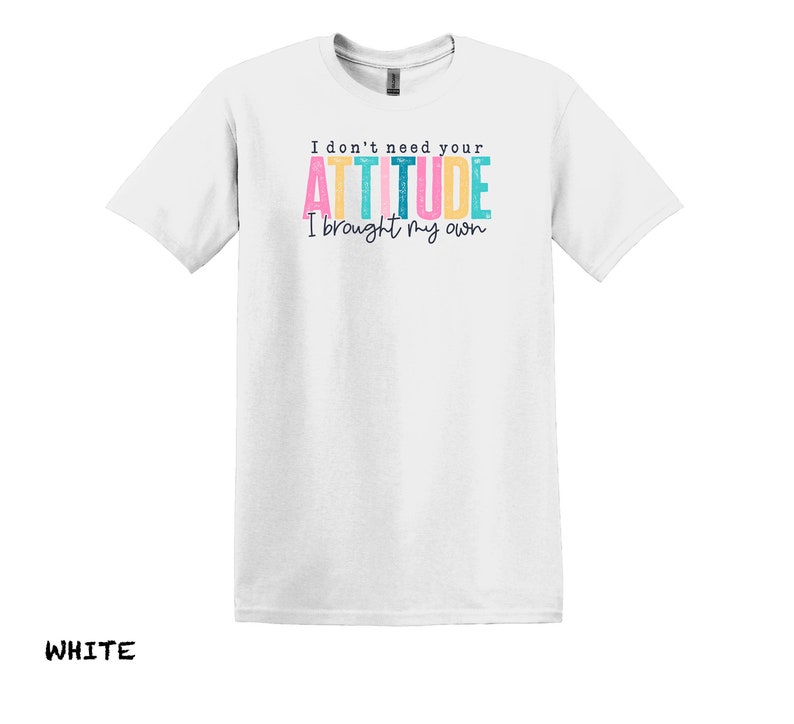 K&ouml;nnte beinhalten: Wei&szlig;es T-Shirt mit dem Text "I don't need your ATTITUDE I brought my own" in bunten Buchstaben.