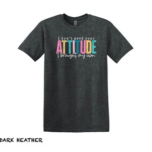 K&ouml;nnte beinhalten: Dunkelgraues T-Shirt mit dem Text "I don't need your ATTITUDE I brought my own" in bunten Buchstaben.
