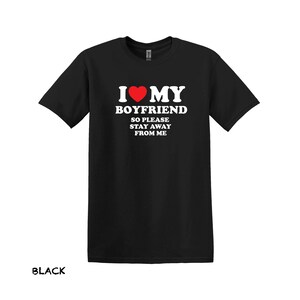 May include: Black t-shirt with white text that reads "I love my boyfriend so please stay away from me". A red heart is in the text.