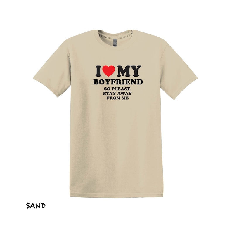 May include: A sand-colored t-shirt with the text "I love my boyfriend so please stay away from me" and a red heart.