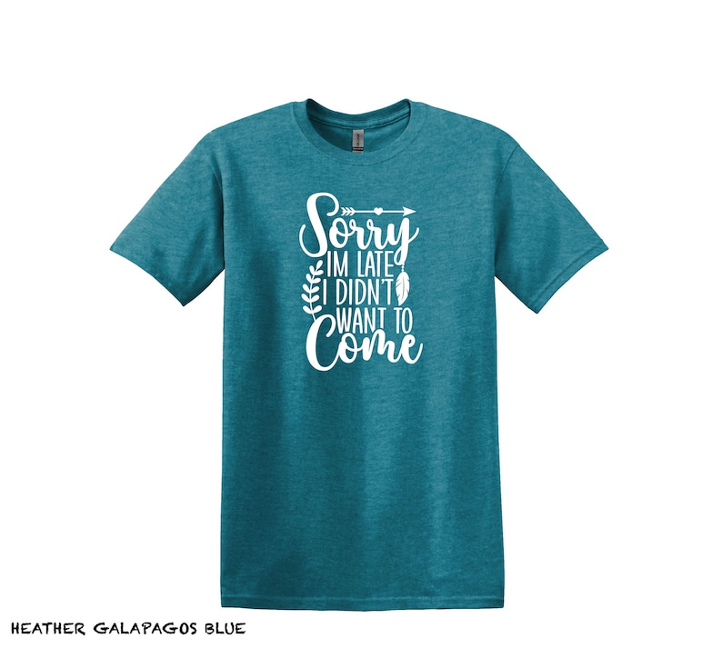 K&ouml;nnte beinhalten: Ein blaues T-Shirt mit dem Text "Sorry, ich bin zu sp&auml;t, ich wollte nicht kommen" in wei&szlig;en Buchstaben mit einem kleinen Pfeil- und Federdesign.