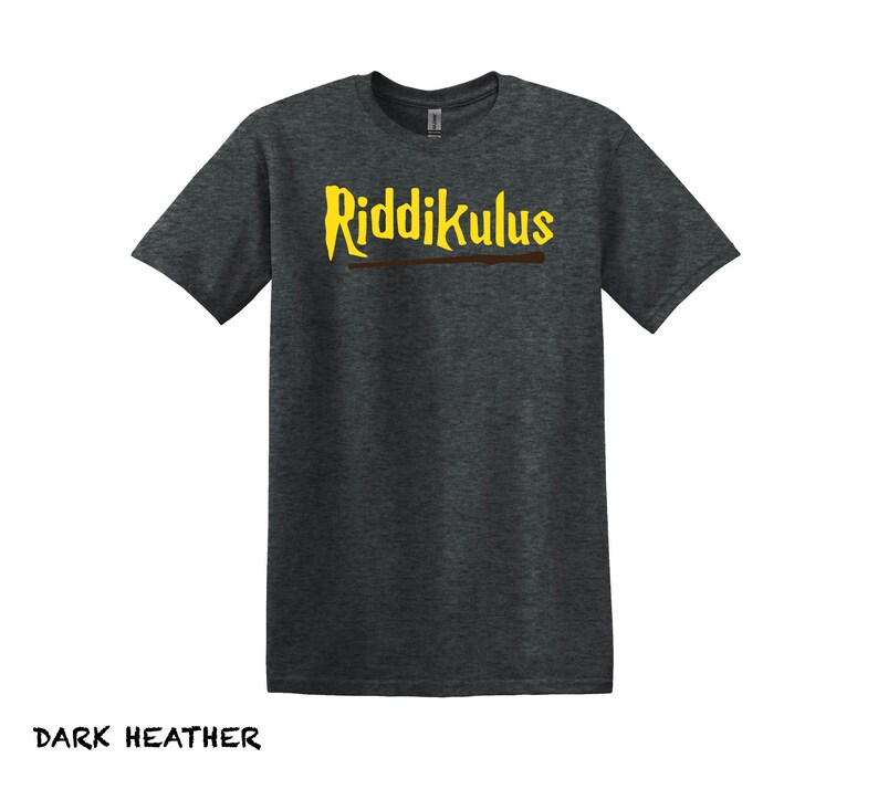 Pode incluir: Camiseta cinza escuro com o texto "Riddikulus" em letras amarelas e uma varinha marrom por baixo.