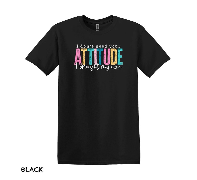 K&ouml;nnte beinhalten: Schwarzes T-Shirt mit dem Text "I don't need your ATTITUDE I brought my own" in bunten Buchstaben.