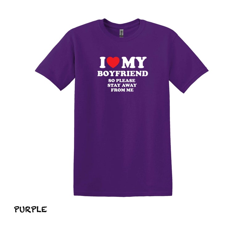 May include: Purple t-shirt with white text that reads "I love my boyfriend so please stay away from me". A red heart is in the text.