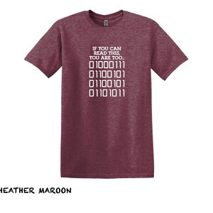 K&ouml;nnte beinhalten: T-Shirt in Heidekraut-Maroon mit dem Text "IF YOU CAN READ THIS, YOU ARE TOO..." und einer Reihe von Bin&auml;rcode: "01000111 01100101 01100101 01101011".