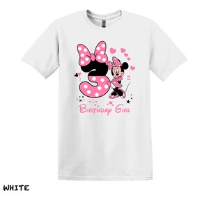 May include: White t-shirt with a pink Minnie Mouse graphic. Minnie is holding a pink number 3 with white polka dots. The text "Birthday Girl" is below the graphic.