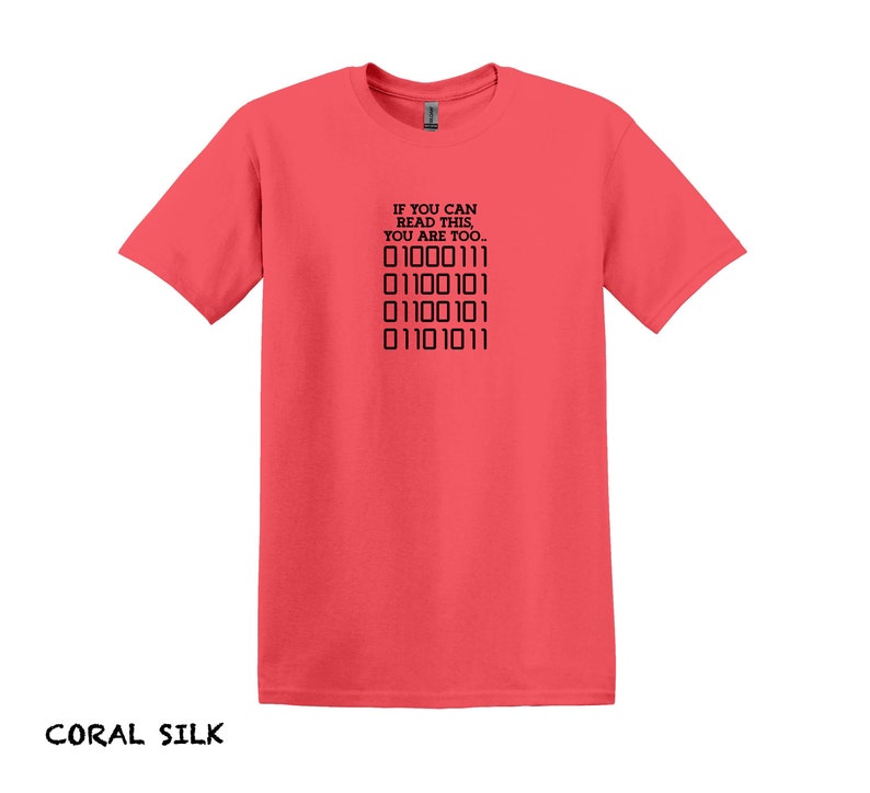 K&ouml;nnte beinhalten: T-Shirt aus Korallen-Seide mit einem schwarzen Aufdruck, der "Wenn du das lesen kannst, bist du es auch." lautet, und einer Reihe von Bin&auml;rcode: "01000111 01100101 01100101 01101011".