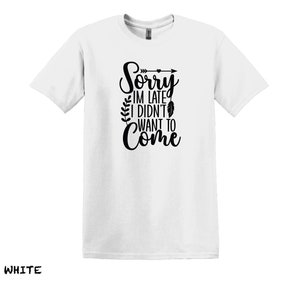 K&ouml;nnte beinhalten: Wei&szlig;es T-Shirt mit schwarzem Text, der "Sorry, ich bin zu sp&auml;t, ich wollte nicht kommen" lautet, mit einer kleinen Pfeil- und Federgrafik.