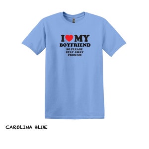 May include: Light blue t-shirt with a black graphic that says "I love my boyfriend so please stay away from me". The graphic includes a red heart.
