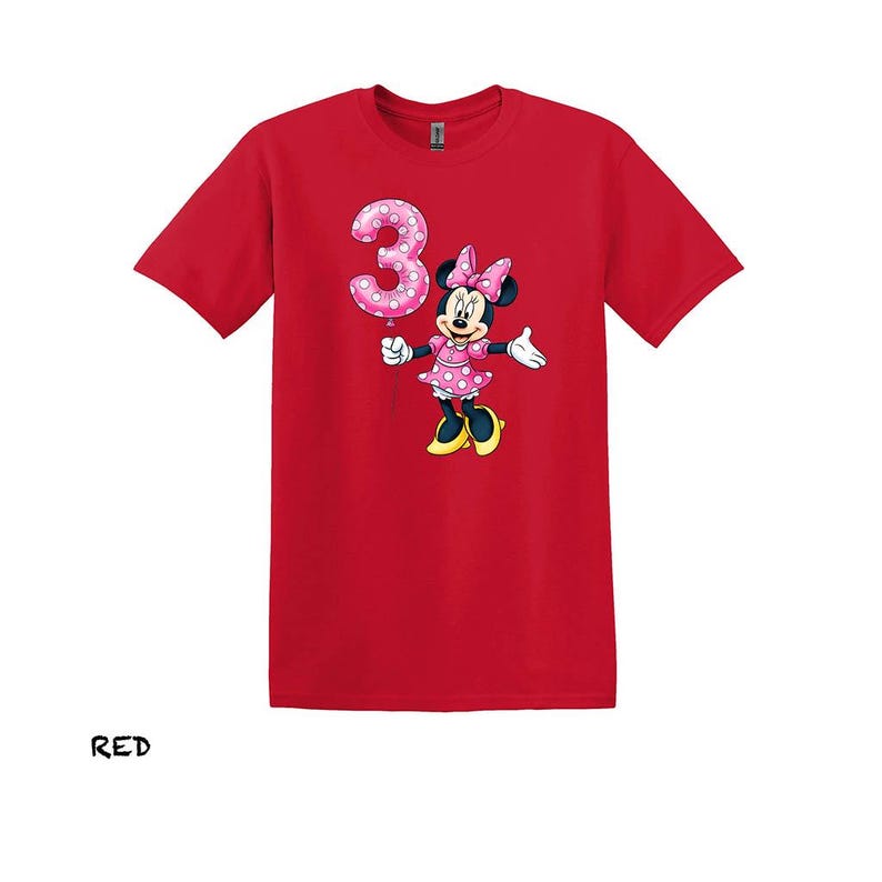 May include: Red t-shirt with a Minnie Mouse graphic holding a pink number 3 balloon. Minnie Mouse is wearing a pink polka dot dress and bow. The word "RED" is printed at the bottom of the shirt.