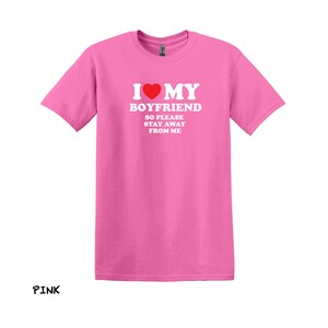 May include: Pink t-shirt with the text "I love my boyfriend so please stay away from me" in white letters with a red heart.