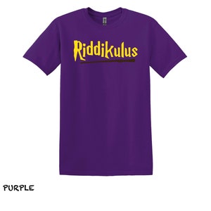 Pode incluir: Camiseta roxa com o texto "Riddikulus" em letras amarelas e um gr&aacute;fico de varinha marrom.