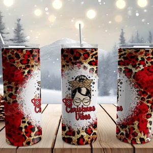 May include: Three stainless steel tumblers with a red and gold leopard print design. The center tumbler features a cartoon illustration of a woman with a bun in her hair and the text "Christmas Vibes".