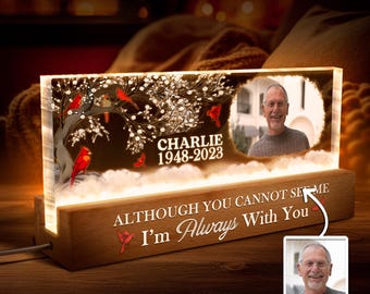 May include: A wooden memorial night light with a clear glass panel featuring a snowy winter scene with cardinals and the text "Charlie 1948-2023". The base of the light has the text "Although you cannot see me I'm always with you".
