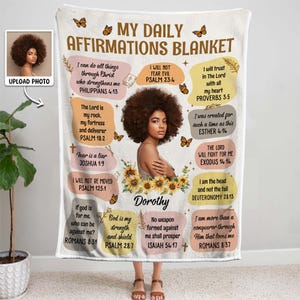 May include: A white fleece blanket with a floral design and inspirational quotes. The blanket features a photo of a woman with an afro and the text "My Daily Affirmations Blanket".