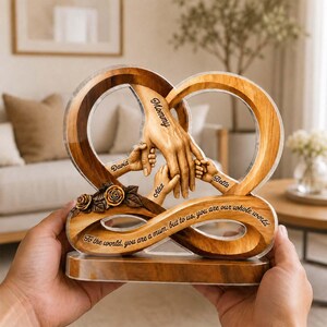 May include: A wooden heart-shaped sculpture featuring a large hand holding three smaller hands. The sculpture includes the names Mommy, David, Alex, and Bella, and the text: To the world, you are a mum, but to us, you are our whole world.