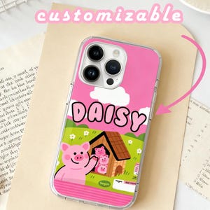Puede incluir: Funda de teléfono transparente con fondo rosa. Presenta un cerdo de dibujos animados saludando, una casa de cerdos y el nombre "DAISY" en letras blancas. La palabra "customizable" está escrita encima.