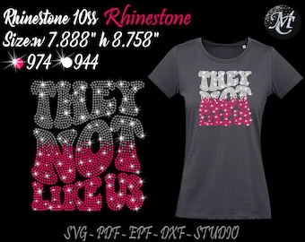 May include: A gray t-shirt with the words "THEY NOT LIKE US" in rhinestone letters. The letters are silver and pink. The shirt is 7.888 inches wide and 8.758 inches tall. The design is made with 974 silver rhinestones and 944 pink rhinestones.