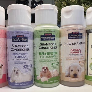 May include: Five bottles of Alpha Dog Series Premium Choice dog shampoo and conditioner. The bottles are labeled with different scents and formulas, including Puppy, Bright White, Safe & Effective, Oatmeal, and Soothing. Each bottle features a dog on the label.