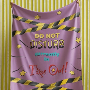 May include: Purple throw blanket with black and yellow caution tape stripes and the text "DO NOT DISTURB currently in Time Out!" in colourful letters.